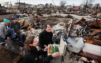 Rosemary McDermott and her husband Anthony Minor react as they open a safe containing a family genealogy they were able to salvage from the basement of her mother's home in the Breezy Point section of the Queens borough of New York, Thursday, Nov. 15, 2012. A fire destroyed more than 100 homes in the oceanfront community during Superstorm Sandy. On the left are Todd Griffin and Kevin Striegle, volunteers with Adventures in Missions, who helped find the safe beneath the rubble. (AP Photo/Mark Lennihan)