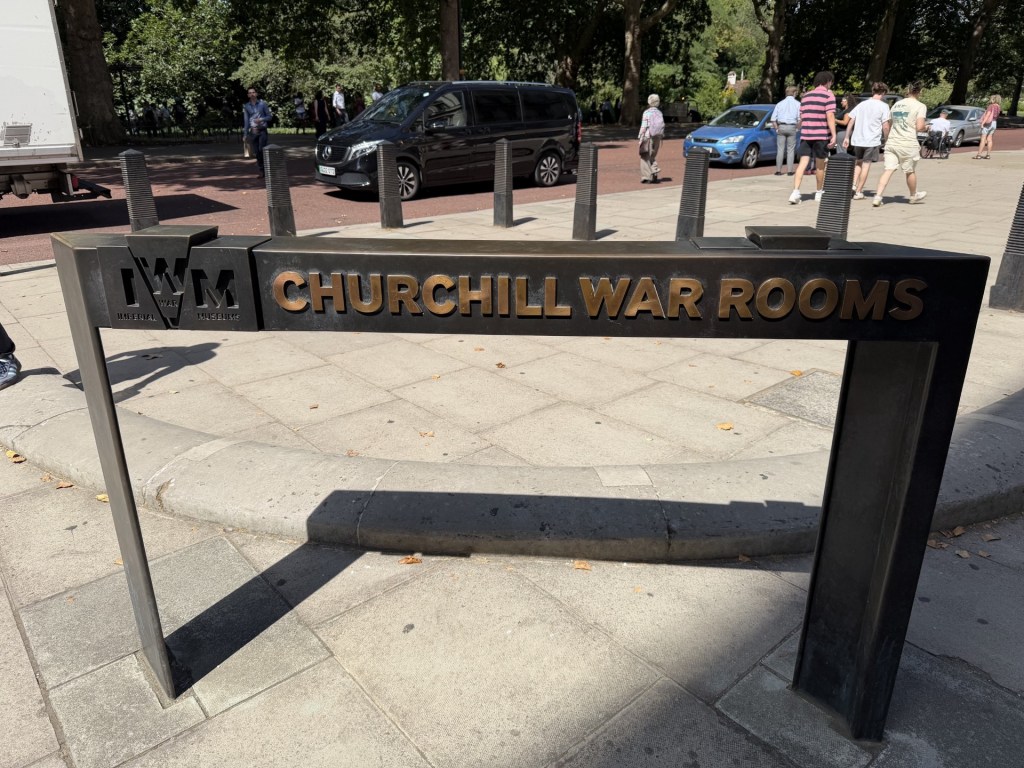 Sign displaying 'Churchill War Rooms' and 'IWM' located at the entrance to the museum in a public area.
