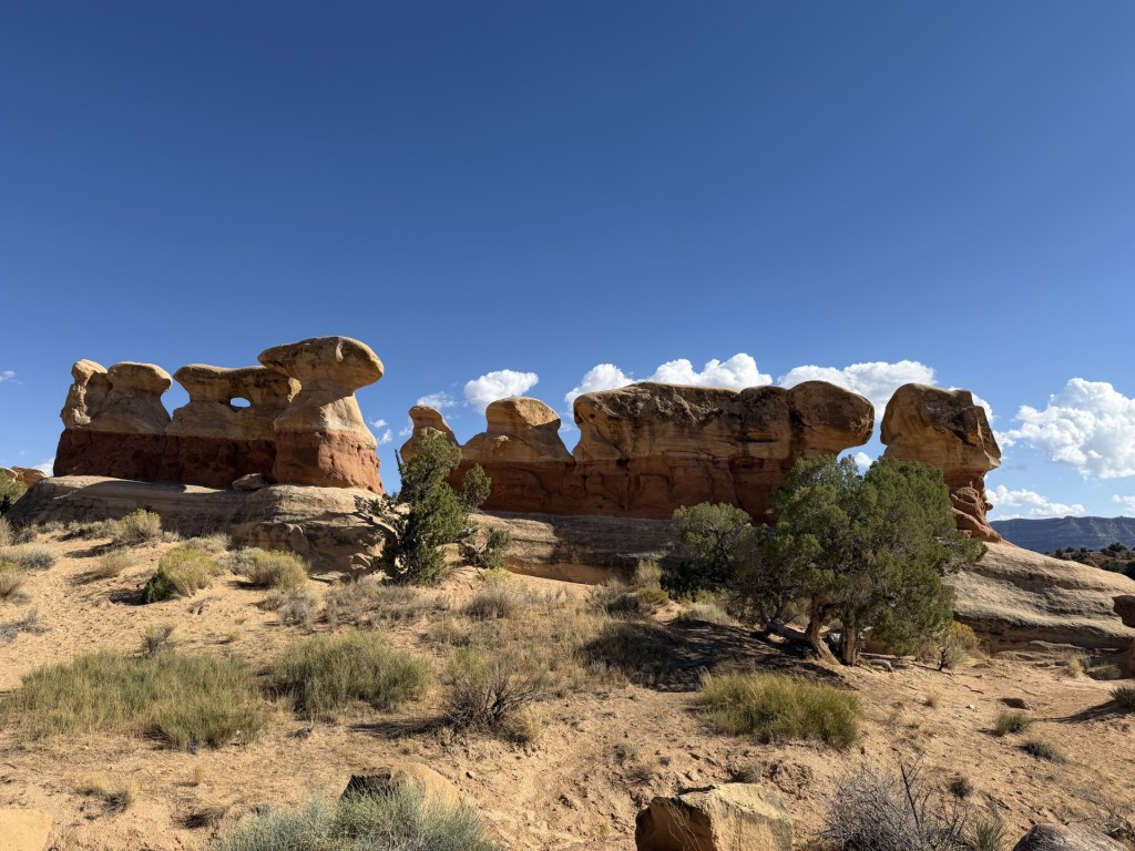 Rock formations in a desert landscape under a blue sky with clouds